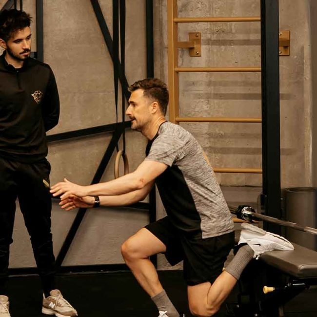 Entrenador personal supervisando a un cliente mientras hace un ejercicio